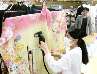 着物にアイロンをかける坂口美紀さんと西田晃三社長＝洲本市中川原町中川原、いせや写真館