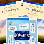 みなと銀行が信託業務を営む認可を受けたことを伝えるチラシ（手前）。パンフレットでも従来（奥右）と異なり、「みなとの遺言信託」と書けるようになった