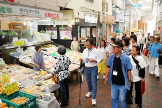東山商店街を視察する台湾桃園市の商業者ら。手前は神戸市商店街連合会の高四代会長＝神戸市兵庫区東山町１