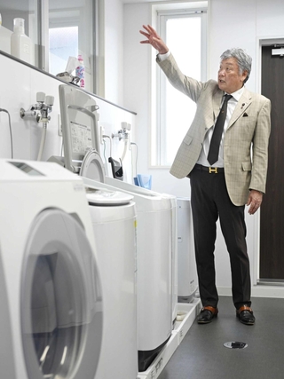 商品の耐久性などを検証するため並べた洗濯機について説明するバリュープランニングの井元憲生社長＝神戸市中央区上筒井通６（撮影・大田将之）