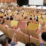 議案の採決時に議決票を挙げるコープこうべの総代ら＝神戸市中央区港島中町６