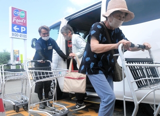 車から降り、店内に入る「買いもん行こカー」の利用者ら＝加古川市東神吉町神吉