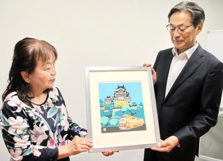 川西祐三郎さんの版画を神姫バスの長尾真社長（右）に手渡す川西和代さん＝神戸市中央区浪花町