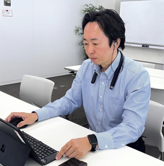 新製品の集音器を装着するソリッドソニックの久保貴弘社長。ブルートゥースで接続すれば、ウェブ会議などにも使える＝神戸市中央区磯上通６