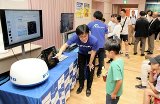 展示する船舶用レーダーについて、子どもたちに説明する古野電気の社員＝西宮市北口町