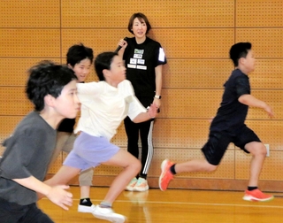 児童らに走り方を伝える寺田明日香さん（奥）＝神戸市立中央体育館