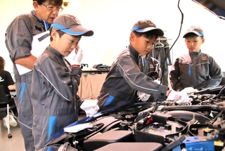 自動車のエンジンオイルの点検を体験する子ども＝神戸市垂水区青山台８、神戸マツダイベントスクエア
