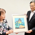 川西祐三郎さんの版画を神姫バスの長尾真社長（右）に手渡す川西和代さん＝神戸市中央区浪花町