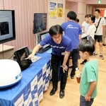 展示する船舶用レーダーについて、子どもたちに説明する古野電気の社員＝西宮市北口町
