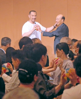 アシックスの個人投資家向け説明会で講演する室伏広治さん（壇上左）。紙風船を使い、参加者全員で体操をした＝神戸市中央区北野町１