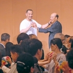 アシックスの個人投資家向け説明会で講演する室伏広治さん（壇上左）。紙風船を使い、参加者全員で体操をした＝神戸市中央区北野町１