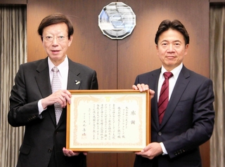三菱ＵＦＪ銀行の北村慎取締役専務執行役員（右）に感謝状を手渡す神戸市の久元喜造市長＝大阪市中央区伏見町３