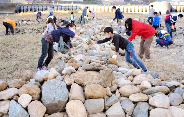 石を積み上げ「生」のオブジェを再生させる親子連れら＝宝塚市の武庫川中州