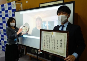 堂安律選手（中央の画面）の代理で感謝状を受け取った憂選手（右）＝尼崎市役所
