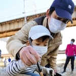 積み上げた石に追悼の思いなどをしたためる親子＝宝塚市の武庫川中州