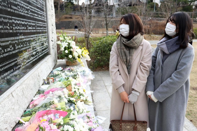 慰霊碑に刻まれた北田明代さんの名前を見つめる和田里佳子さんと瞳さん（右）＝西宮震災記念碑公園