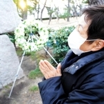 友人に囲まれて笑顔を浮かべる夫の姿を思い浮かべ、手を合わせる小笹昭子さん＝芦屋公園