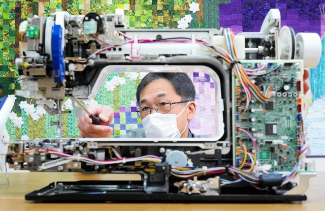 ミシンを修理する藤本崇秀さん＝宝塚市伊孑志、ミシンのフジモト
