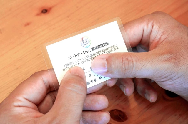 尼崎市から交付されたパートナーシップ宣誓書受領証を手にする男性＝尼崎市内