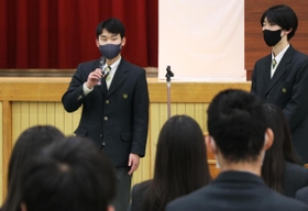 体育館でポッキーの配布について発表する肥後知磨さん（左）＝芦屋市新浜町、国際高校