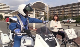 白バイ隊員が女性のながら運転を注意する場面（武庫川女子大学提供）
