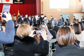 卒業式会場を後にする生徒を収めようとスマートフォンを構える保護者ら＝西宮市神原、大社中学校