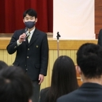 体育館でポッキーの配布について発表する肥後知磨さん（左）＝芦屋市新浜町、国際高校