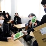 教室で同級生にポッキーを配る肥後知磨さん（右）＝芦屋市新浜町、県立国際高校