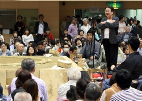 土俵下のお立ち台に上り、あいさつをする宝塚市の中川智子市長（奥右）＝２０１８年４月、宝塚市立スポーツセンター総合体育館