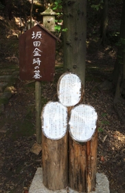 坂田金時の墓の前にある説明書きが貼られたヒノキ材。スキットルに似ている＝川西市満願寺町