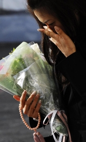 目頭を押さえ、現場に花を手向ける参列者＝２０１３年４月２５日午前７時３９分、尼崎市久々知３