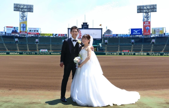 グラウンドで結婚記念の写真を撮影する新郎新婦＝２３日、西宮市甲子園町、阪神甲子園球場