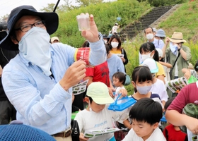 子どもたちが捕まえた昆虫について解説する「自然と文化の森協会」の佐藤亮会長（左）＝２０２０年１０月４日、猪名川河川敷