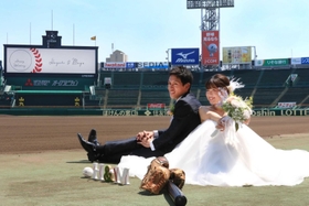 グラウンドで結婚記念の撮影をする新郎・堀北勇人さんと新婦・麻由さん＝２３日、西宮市甲子園町、阪神甲子園球場