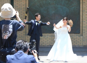 球場の外周でバットとグローブを持ち、撮影に応じる新郎新婦＝２３日、西宮市甲子園町、阪神甲子園球場
