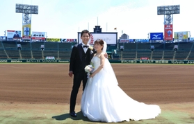 グラウンドで結婚記念の写真を撮影する新郎新婦＝２３日、西宮市甲子園町、阪神甲子園球場