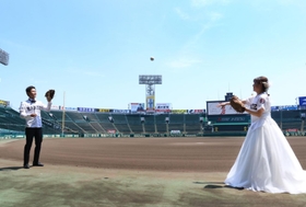 ファーストバイトならぬファーストキャッチボールをする新郎新婦＝２３日、西宮市甲子園町、阪神甲子園球場