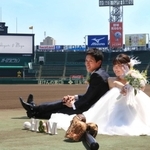 グラウンドで結婚記念の撮影をする新郎・堀北勇人さんと新婦・麻由さん＝２３日、西宮市甲子園町、阪神甲子園球場