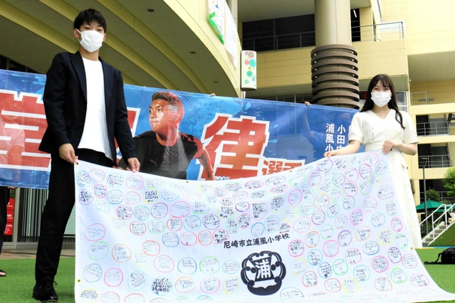 堂安律選手へのメッセージ入り応援旗を持つ兄の憂さん（左）＝あまがさきキューズモール