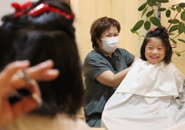 医療用かつらに役立ててもらおうと、腰まで伸びた髪を切ってもらう野口史貴ちゃん＝西宮市若松町、フィアクレー