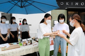 販売開始日に店先で豆蜂の試食を勧める武庫川女子大の学生＝神戸市東灘区御影石町４