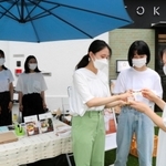 販売開始日に店先で豆蜂の試食を勧める武庫川女子大の学生＝神戸市東灘区御影石町４