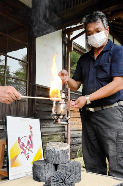 川西市黒川地区で生産される「菊炭」から火がともされたランタンを手にする炭焼き農家の今西学さん＝黒川公民館