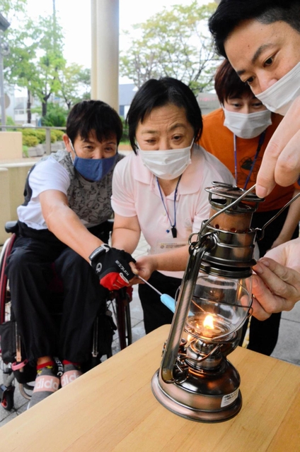 福祉作業所の利用者が手作りしたろうそくでランタンに火をともす参加者＝伊丹市昆陽池２、市立障害者福祉センター