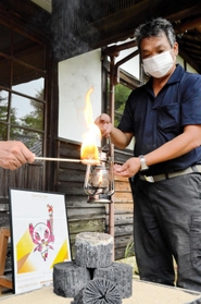 川西市黒川地区で生産される「菊炭」から火がともされたランタンを手にする炭焼き農家の今西学さん＝黒川公民館