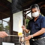 川西市黒川地区で生産される「菊炭」から火がともされたランタンを手にする炭焼き農家の今西学さん＝黒川公民館