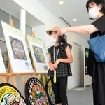 川西市ゆかりのデザインマンホールふたを見学する親子＝川西市郷土館