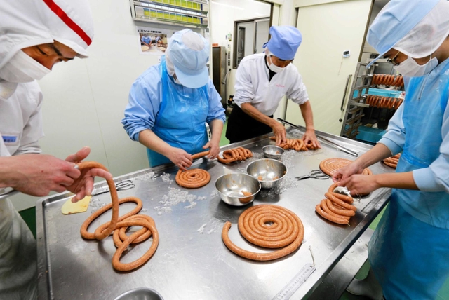 羊の腸に肉詰めする利用者ら＝尼崎市名神町２、しんわ名神工場（提供）
