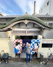 開業当初から残る唐破風屋根。奥には高さ２５メートルの煙突がのぞく＝第一敷島湯