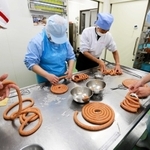 羊の腸に肉詰めする利用者ら＝尼崎市名神町２、しんわ名神工場（提供）